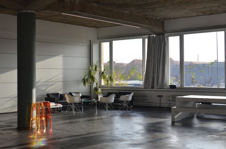 Spacious modern loft interior featuring minimalist furniture and large windows with natural light.